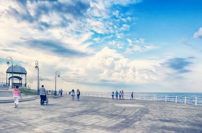 People on beach against cloudy sky