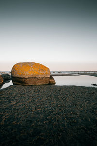 Rocks by sea against clear sky during sunset