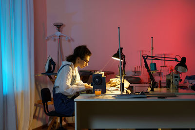 Tailoring business young girl designer sewing clothes in studio using electric machine and fabric