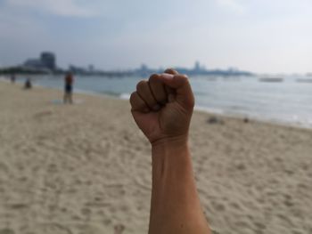 Midsection of person on sand at beach against sky