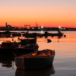 Boats moored in sea against orange sky