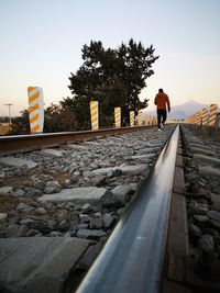 Rear view of man on railroad track against sky