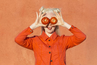 Portrait of man holding apple against orange background