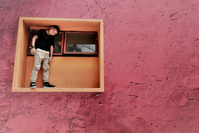 Woman standing against pink wall