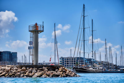 Sailboats moored at harbor against sky