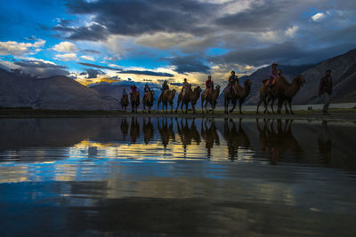 Reflection of people on water against sky