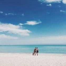 Couple walking in arm around at beach against sky