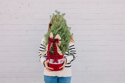 Young woman standing against brick wall
