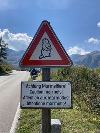 Information sign by road against sky