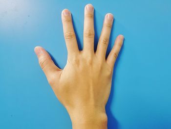 Close-up of human hand against blue background