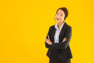 Portrait of a smiling young woman against yellow background