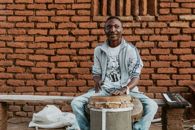 Portrait of a smiling man standing against brick wall