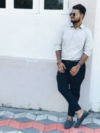 Portrait of young man standing against wall