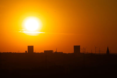 Silhouette buildings against orange sky during sunset