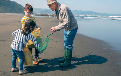 Grandfather with grandchildren cleaning beach