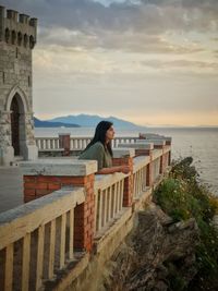 Side view of woman standing by retaining wall in balcony