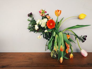Close-up of flowers in vase on table against wall