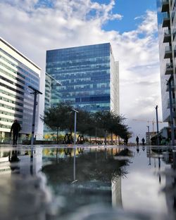 Reflection of buildings in city against sky