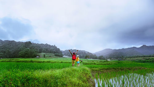 Rear view of woman walking on field against sky