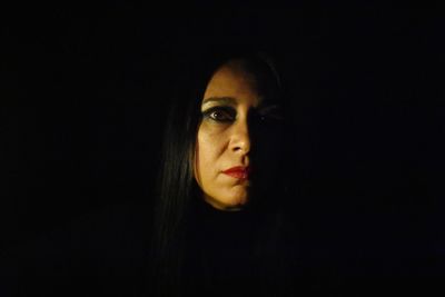 Portrait of young woman against black background