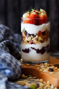 Close-up of strawberries with yogurt and granola in glass on table