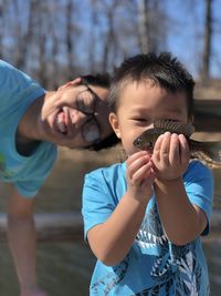 Portrait of smiling father holding fish with son