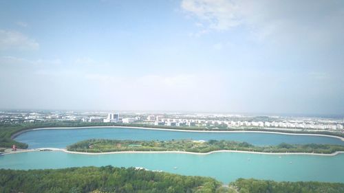 Aerial view of city by sea against sky