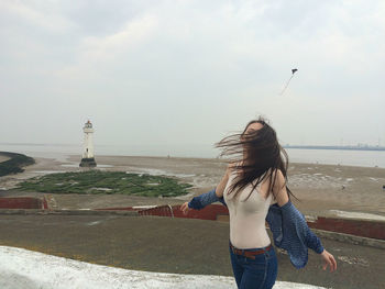 Woman standing by sea against sky