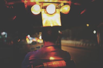 Rear view of man in illuminated room