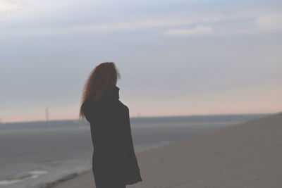 Woman standing at beach during sunset