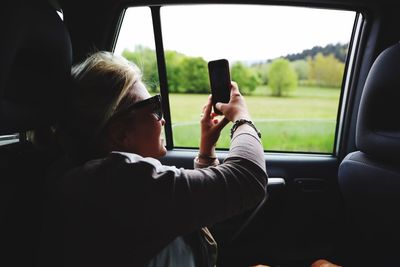 Woman photographing with phone in car