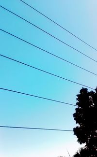 Low angle view of power lines against clear blue sky