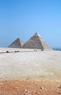 View of desert and pyramids against clear blue sky