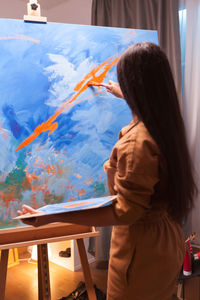 Rear view of woman painting at home