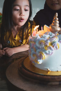 Close-up of sisters blowing birthday candles