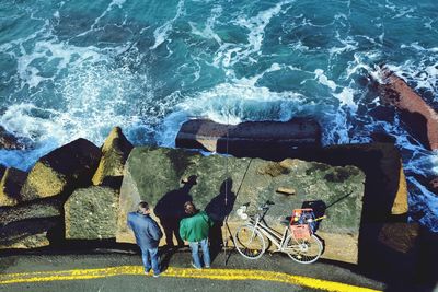 High angle view of people standing on rock by sea