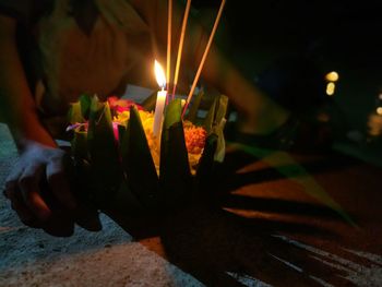 Close-up of hand holding lit candles