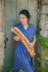 Young woman standing with french baguettes in the countryside