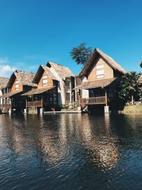 Houses by lake against buildings against clear blue sky