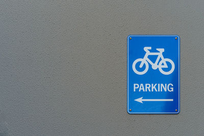 Close-up of bicycle parking sign on gray wall