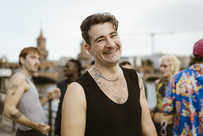 Portrait of smiling gay man with non-binary friends in background