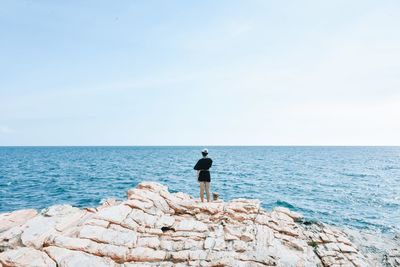 Rear view of man standing in sea against clear sky