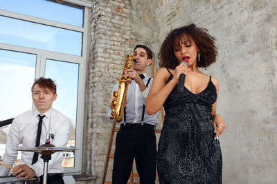 Female singer performing with musicians at loft apartment