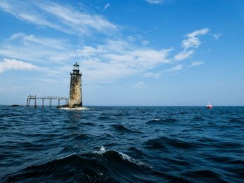 Lighthouse by sea against sky