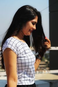 Young woman looking away while standing against wall