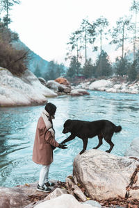 Full length of a woman and a dog in the river bank 