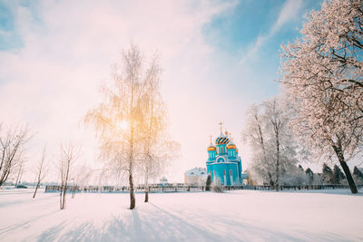 Rear view of woman walking on snow covered field against sky