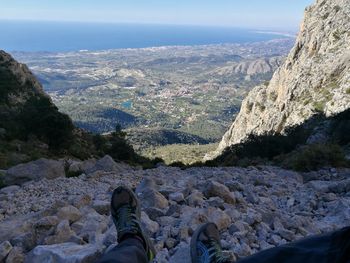 Low section of person on mountain against sky