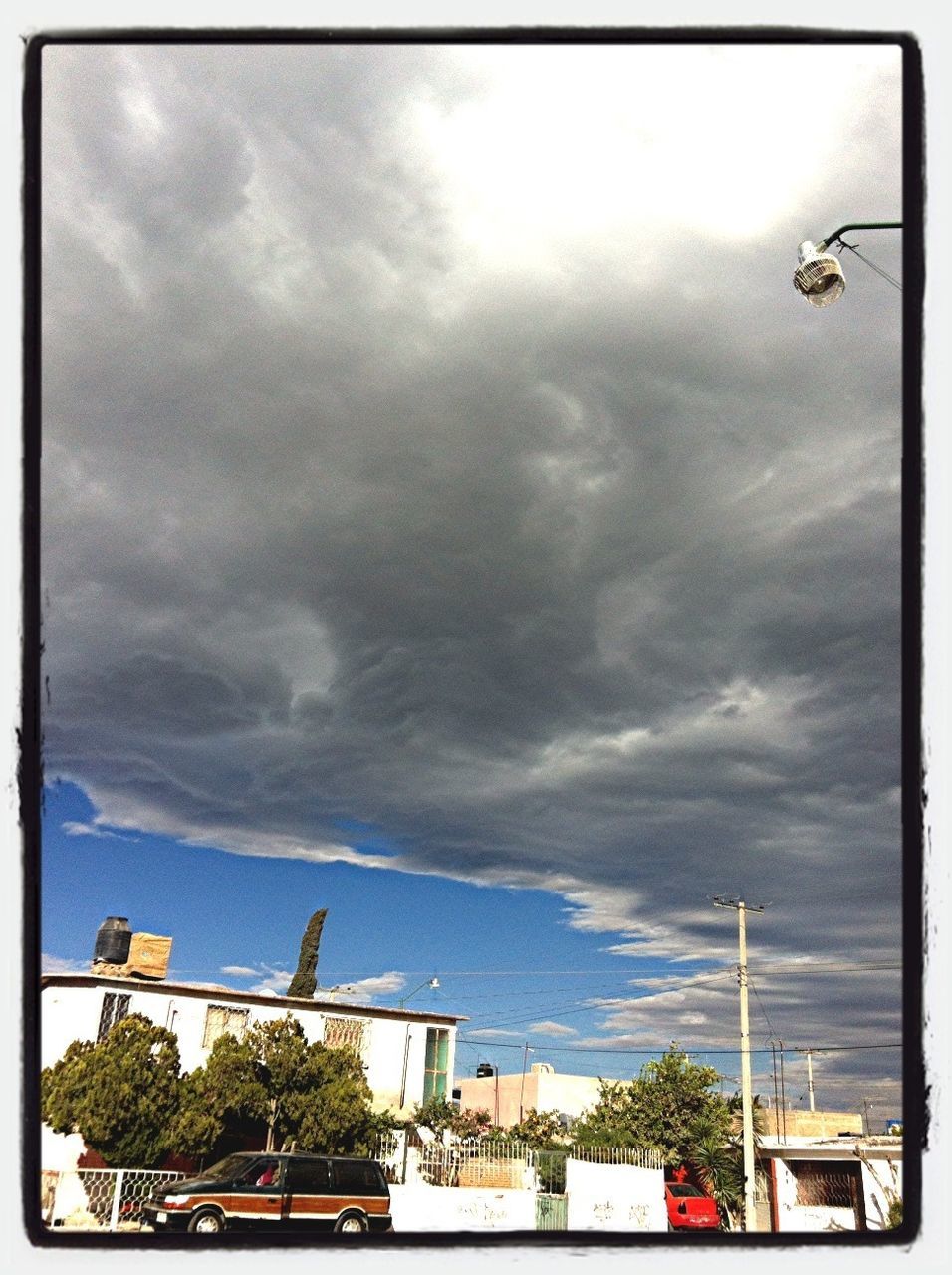 sky, building exterior, built structure, architecture, transfer print, cloud - sky, low angle view, street light, cloudy, auto post production filter, cloud, tree, city, transportation, day, car, outdoors, power line, building, overcast