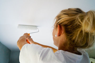 Smiling woman painting wall at home